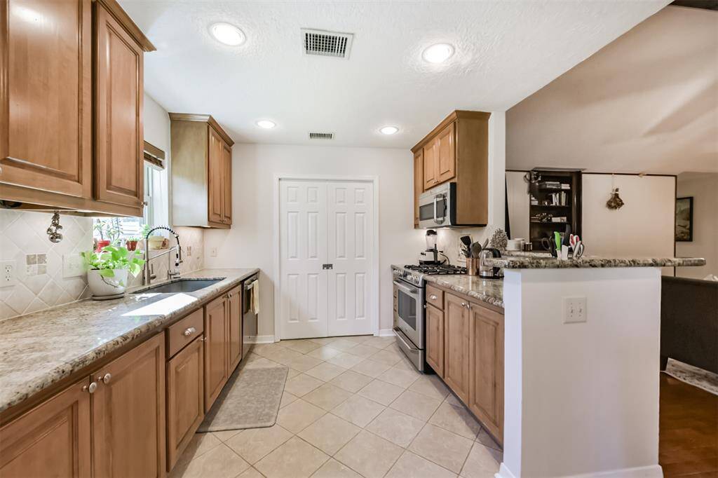 Updated Kitchen with granite countertops, tile backsplash, stainless appliances and deep sink