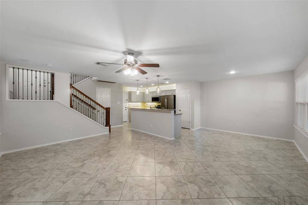 Take in the inviting living room of this charming townhome, featuring a beautifully designed staircase with updated spindle rails and a ceiling fan, adding both style and comfort to the space.