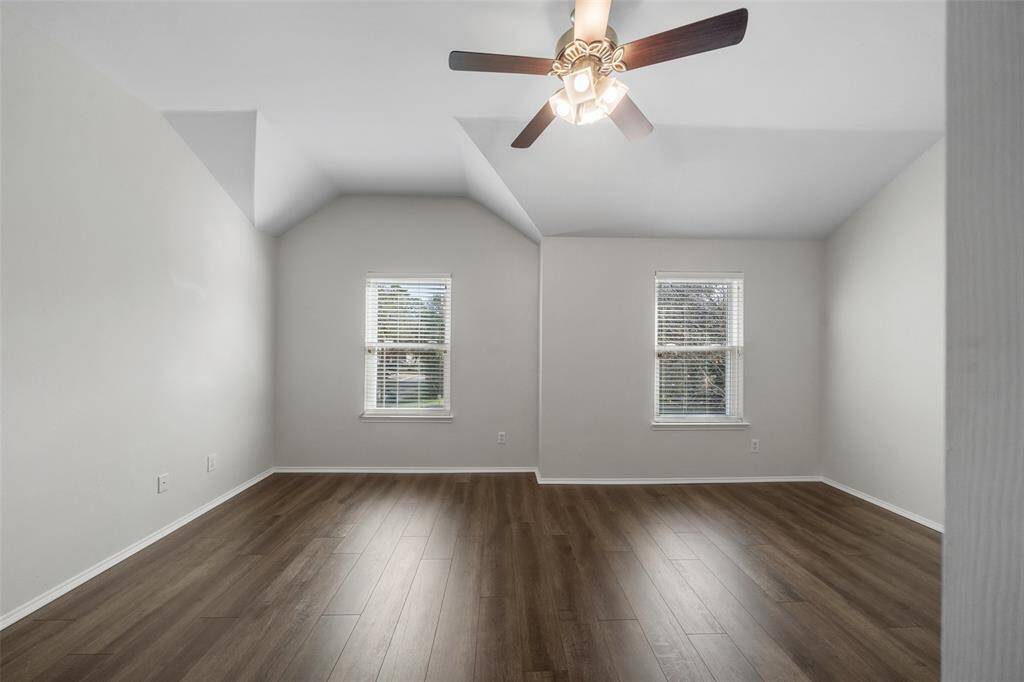 The primary bedroom features new engineered wood floors, soaring high ceilings, a ceiling fan, and insulated windows that allow natural light to fill the space, creating a bright and inviting retreat.