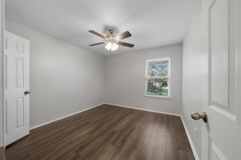 One of the two secondary bedrooms features new engineered wood floors, a ceiling fan, and a peaceful view of the back of the property, providing a serene and comfortable space.