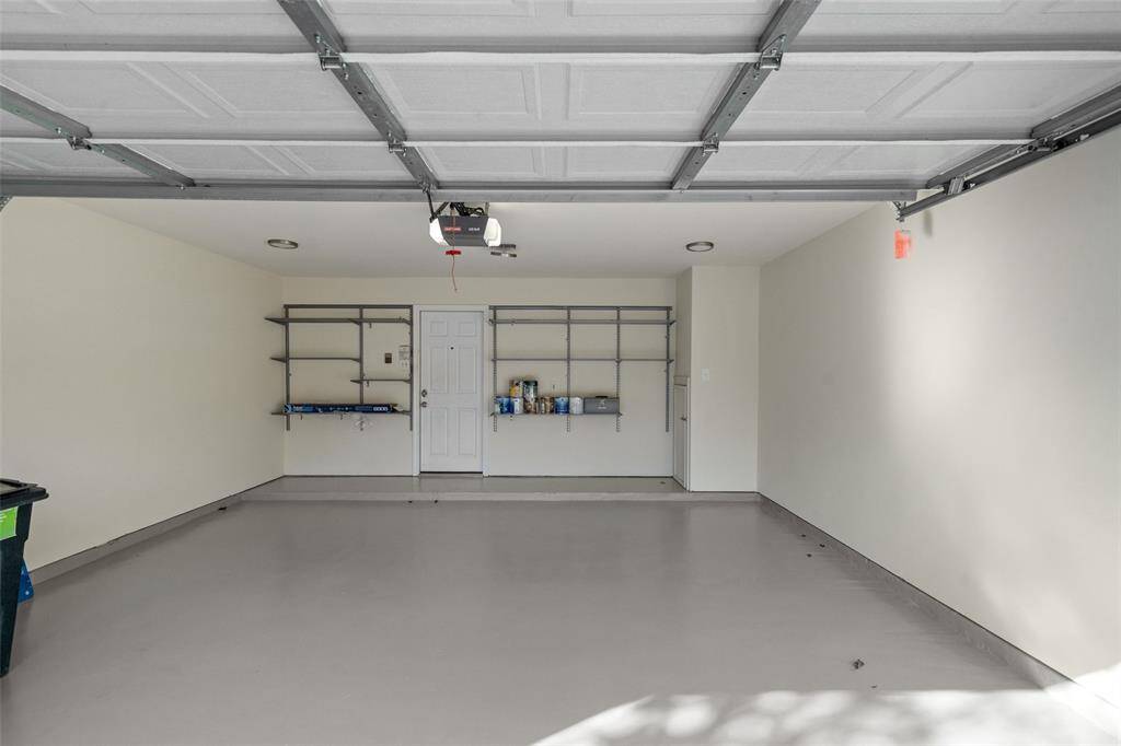 The insulated attached garage features freshly painted floors, container store purchasing shelving, and additional storage space located at the back right, offering both functionality and organization.