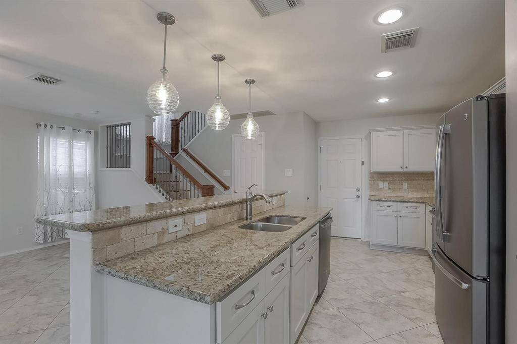 View of thA beautifully updated staircase with elegant iron spindles leads to a spacious open-concept living room and kitchen.