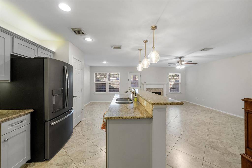Another view of the kitchen highlights the inviting breakfast bar, accented by recessed lighting and stylish pendant lights, creating a warm and functional space for dining and entertaining.
