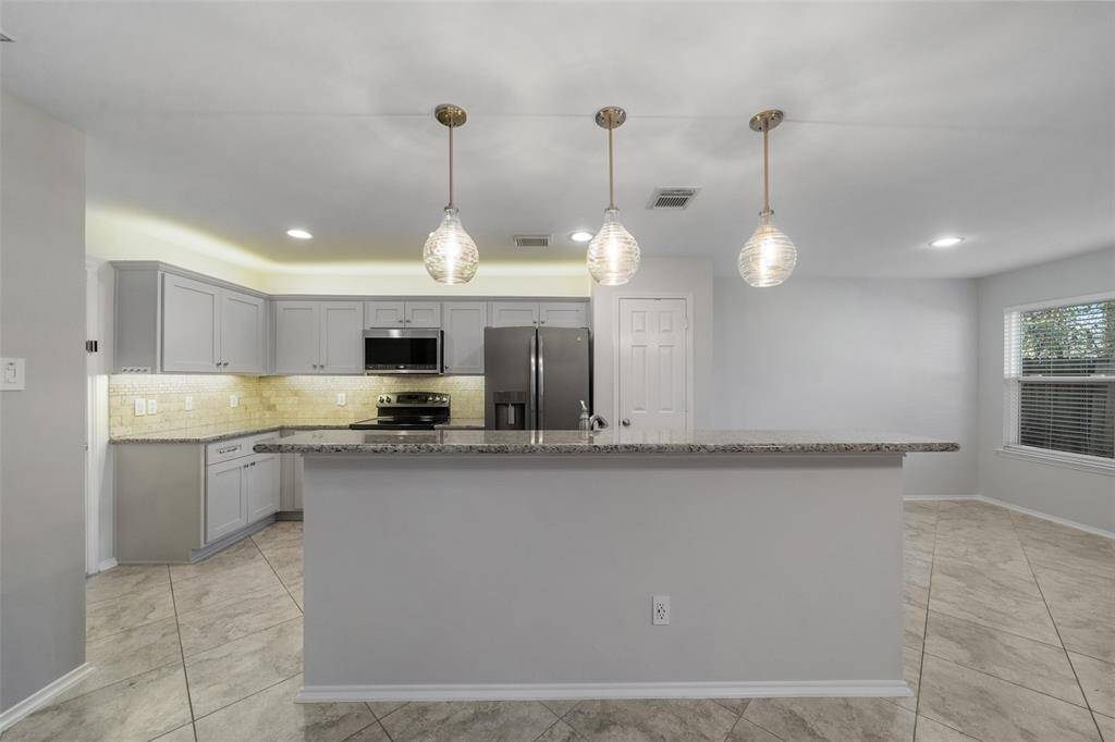 Enjoy a stunning view of the kitchen, featuring newly installed lighting above and below the cabinets, complemented by elegant tile floors that add both style and functionality to the space.