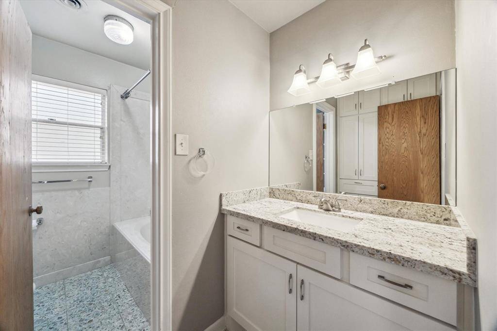 Hall bathroom with granite countertop and undermount sinks, plenty of linen cabinets with updated lighting.  Adjacent is the soaking tub with shower.