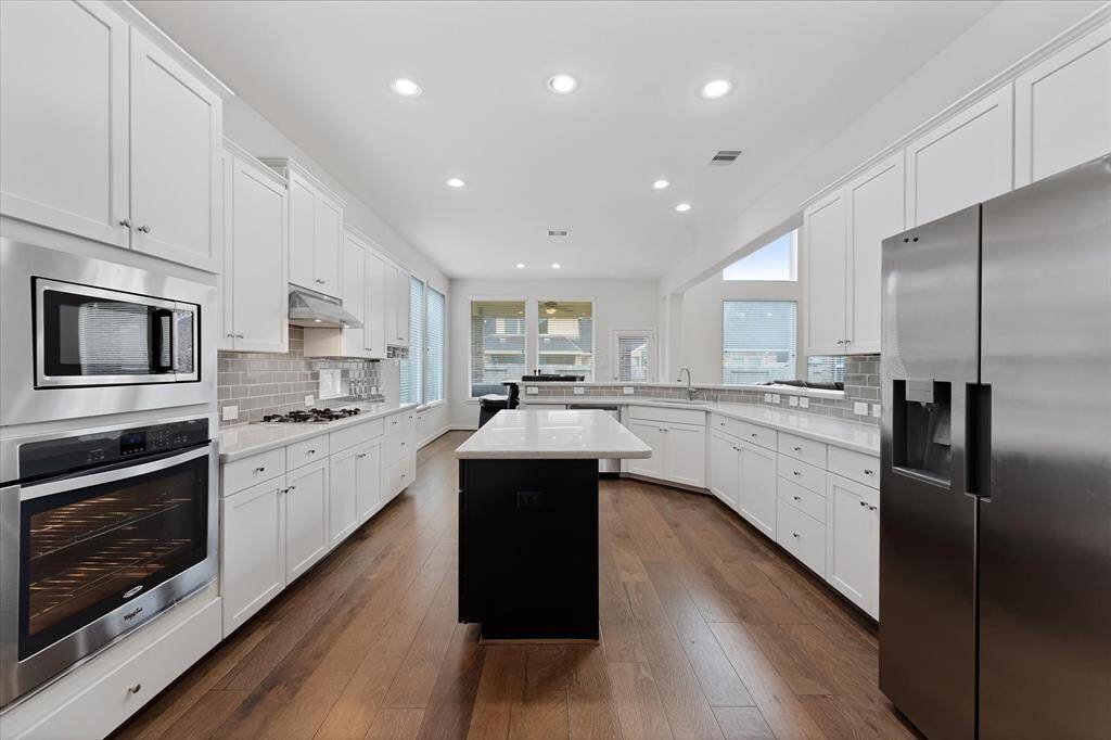 Island kitchen with stainless appliances and white cabinetry