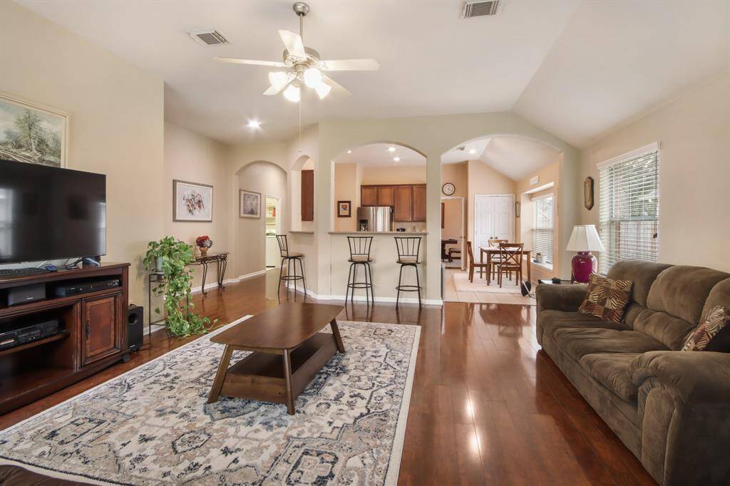 This spacious living area flows seamlessly into a kitchen with a breakfast bar and a dining area with ample natural light, perfect for entertaining and family gatherings.