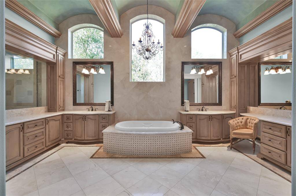 Luxurious mornings and evenings await in this serene spa-like bath featuring marble floors, barrel-vaulted ceilings, his and hers vanities and jacuzzi tub.