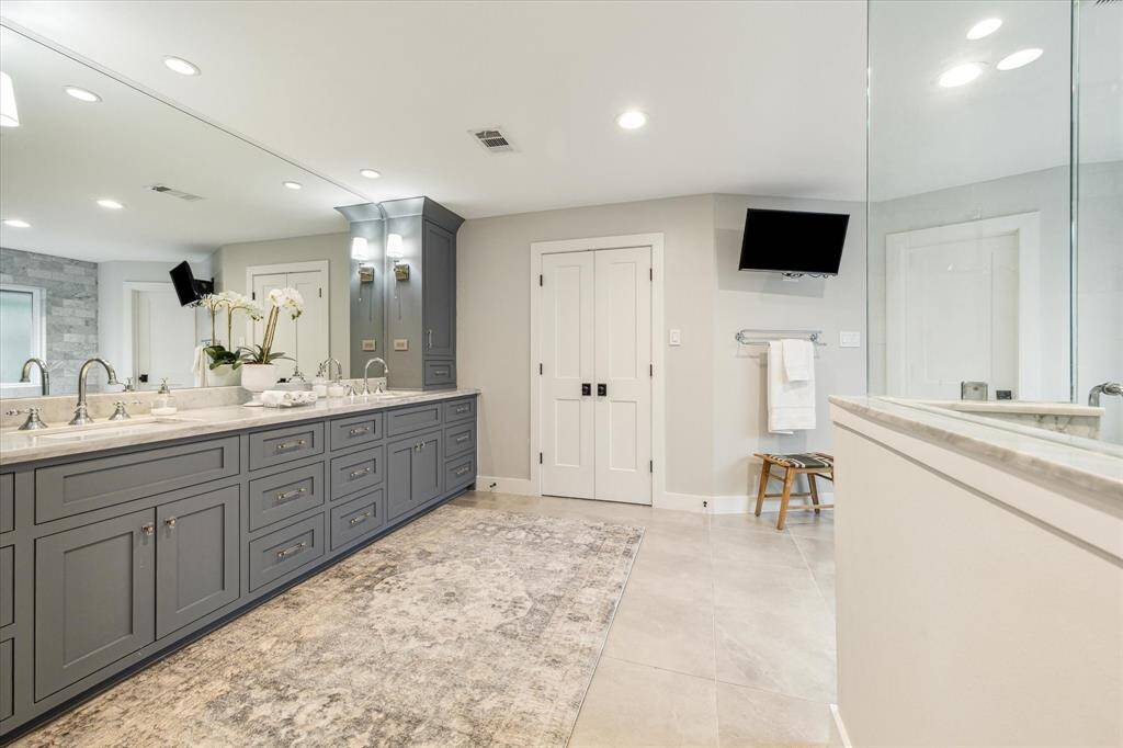 Stunning primary bath with custom cabinets with plenty of storage, dual sinks set in quartz countertops, tand ravertine flooring.