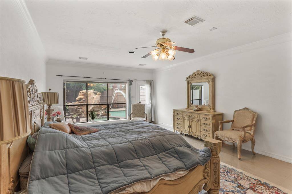 Primary Bedroom on 1st floor with crown molding, marble floors and French doors leading out to stunning backyard.