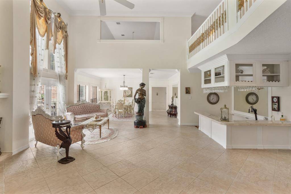Another beautiful view of the gracious formal living area with custom wet bar, high ceilings and stunning landing showing off the custom work in this home.