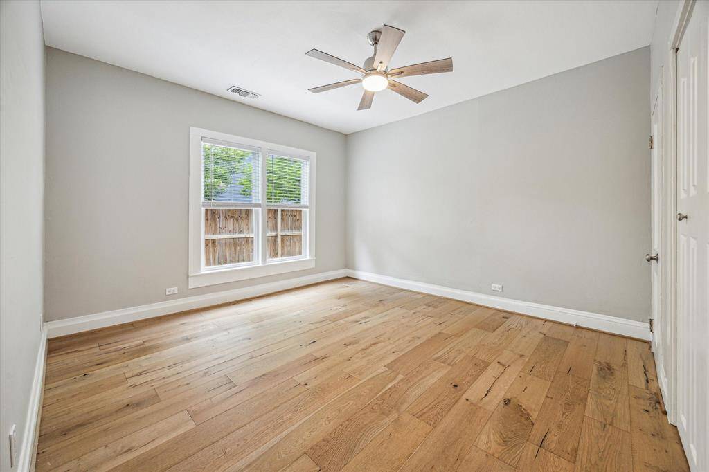 Bedroom with engineered hardwoods, large window, ceiling fan and closet.