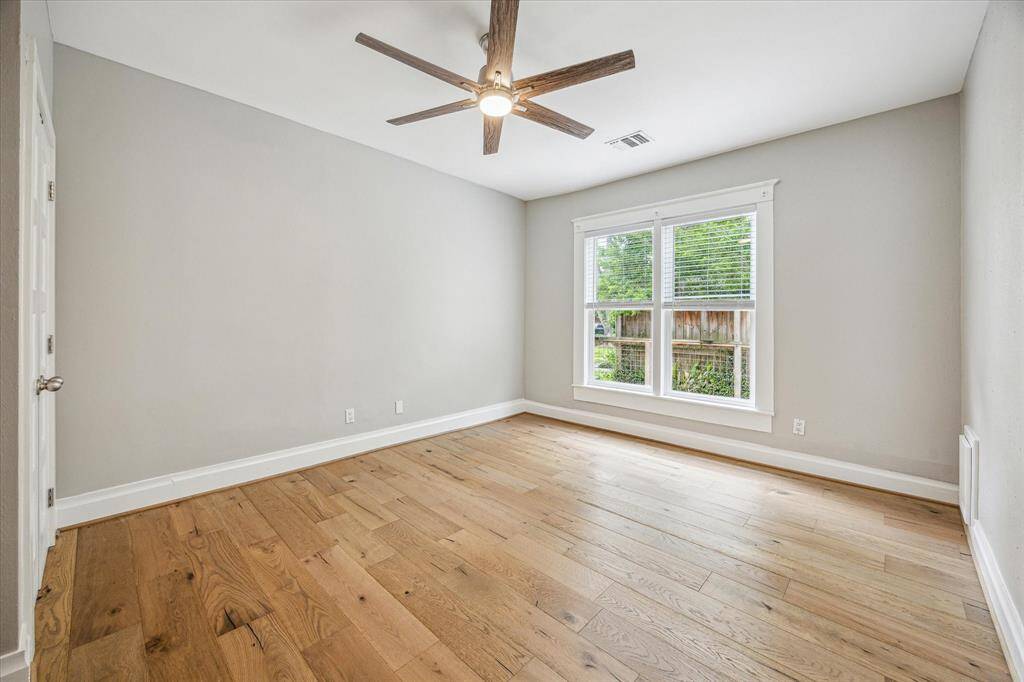 Bedroom with engineered hardwoods, large window, ceiling fan and closet.