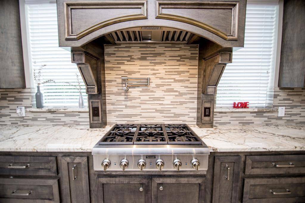 This kitchen features a stylish hood and a premium six-burner Thermador stove, perfect for gourmet cooking.