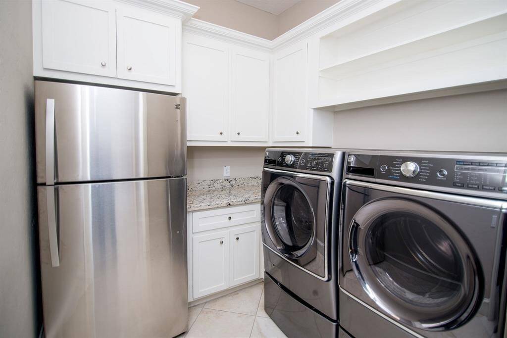 Elegant laundry room featuring modern appliances, ample storage, and a convenient second refrigerator.