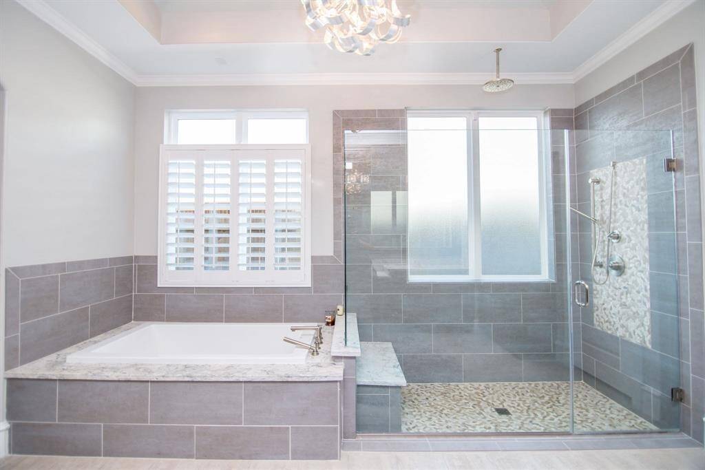 Experience luxury in this spa-like bathroom with a sunken tub, spacious shower, and elegant bench, all enhanced by an overhead showerhead.