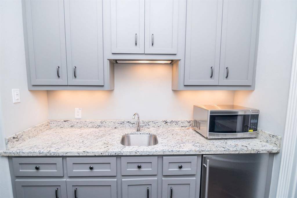 Charming second-floor kitchenette featuring granite countertops and ample storage space.