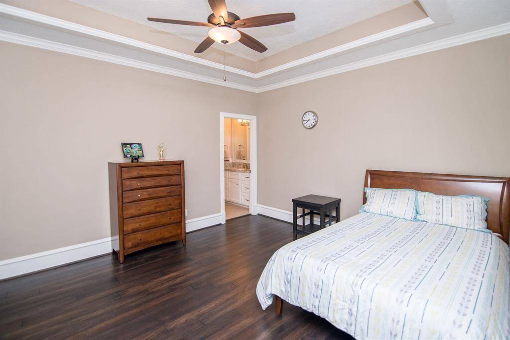 This elegant ensuite bedroom features a striking coffered ceiling and expansive wood flooring.