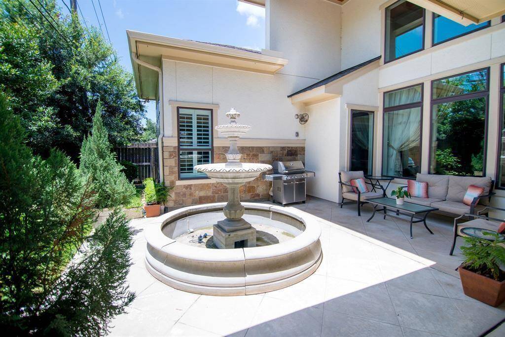 Charming outdoor space featuring a serene water fountain, surrounded by lush greenery, with a mosquito control system for ultimate comfort.