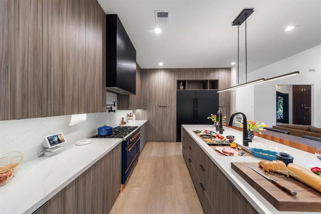 Sleek white quartz countertops that extend as backsplash, sleek cabinetry and high-end professional appliances.