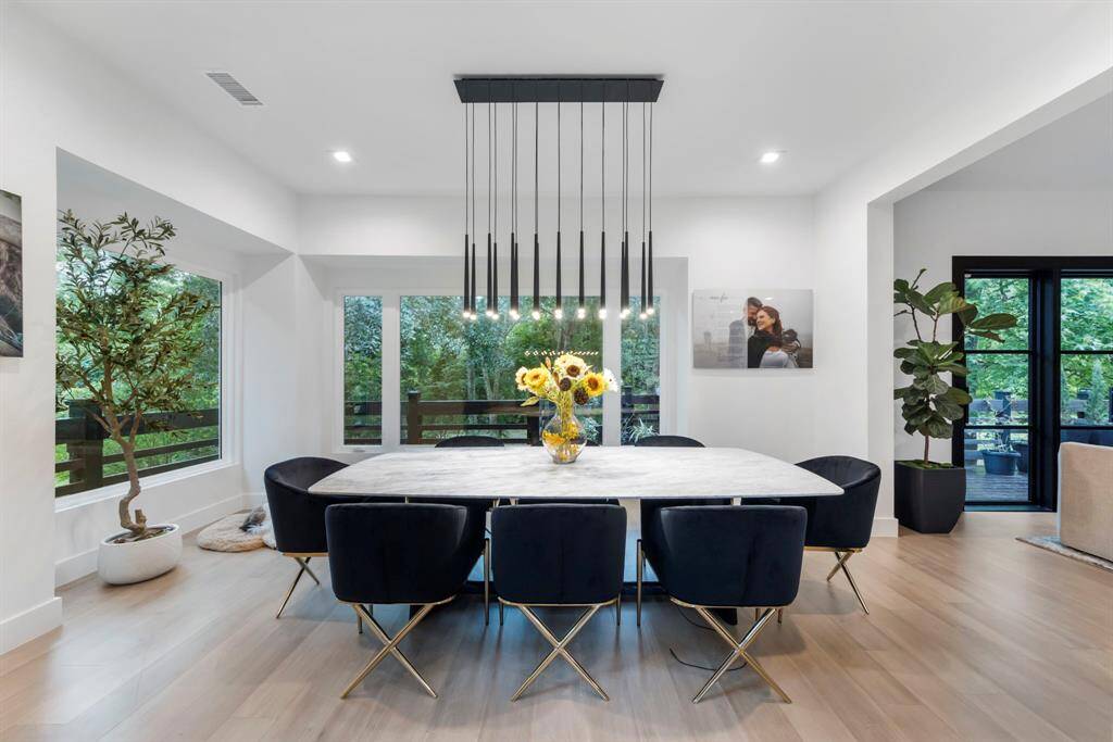 Expansive dining room with walls of windows, wrap around porch and elegant designer lighting.