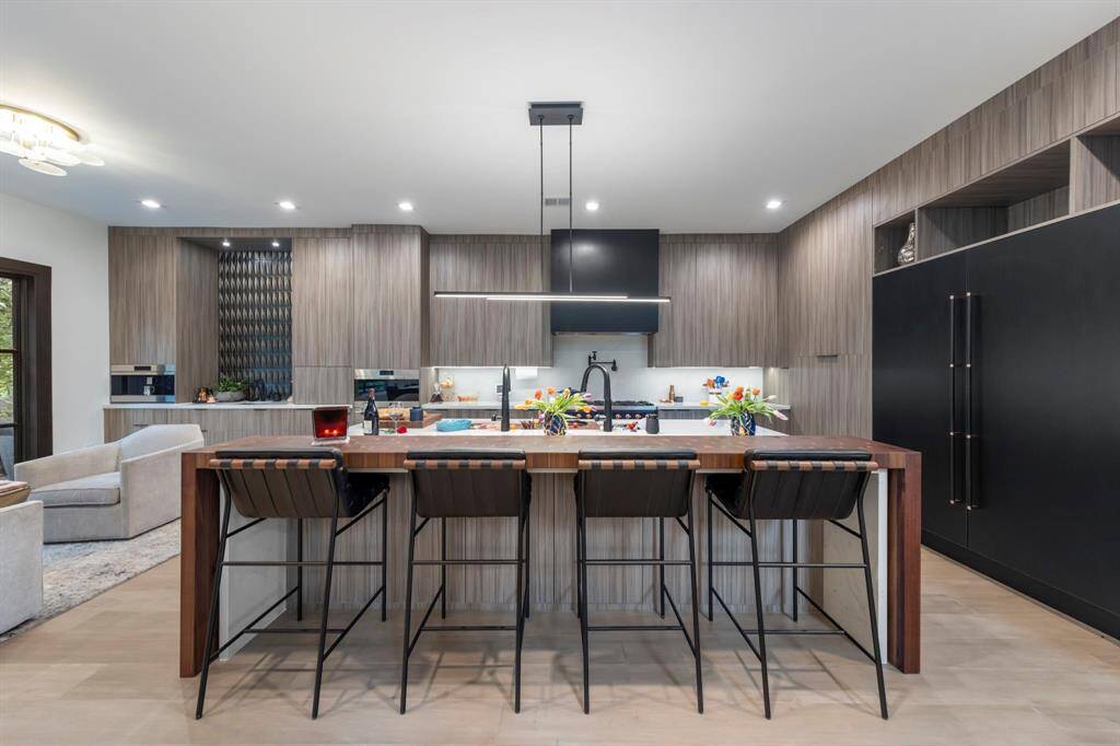 Oversized quartz island with breakfast bar seating and walnut butcher block accent.