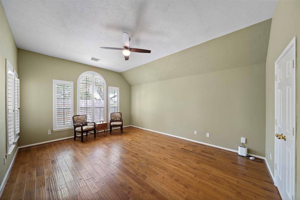 Primary bedroom offers arched plantation shutters and walnut wood flooring.