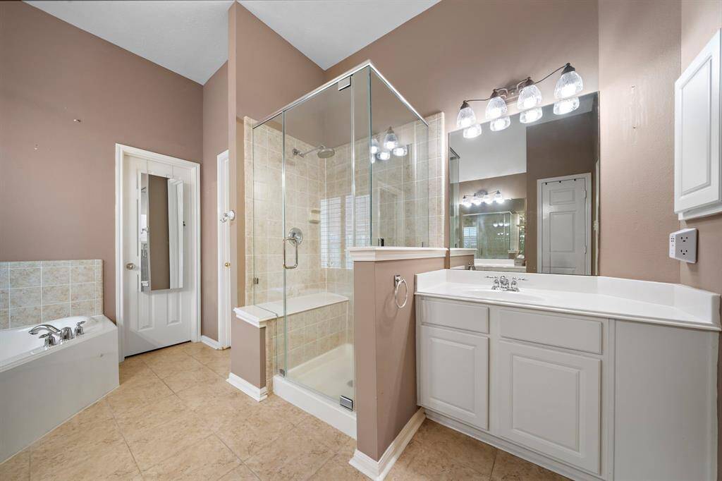 The primary bathroom provides a rain shower head with upgraded shower glass, two separate sink vanities, and garden soaking tub.