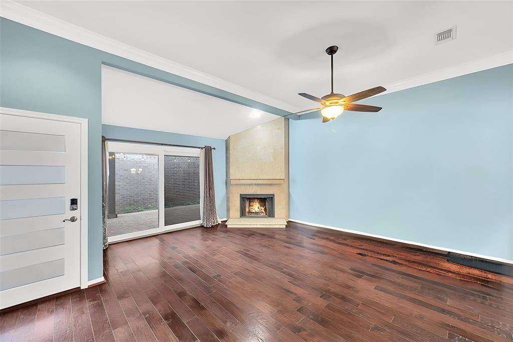 Floor to ceiling double paned glass doors with views of the patio and a gas log fireplace accent this open concept living area.