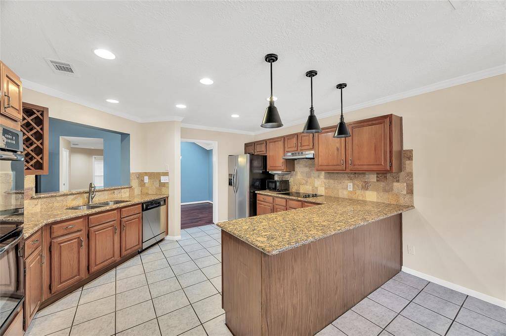 Granite counters, recent pendant lights over the peninsula.