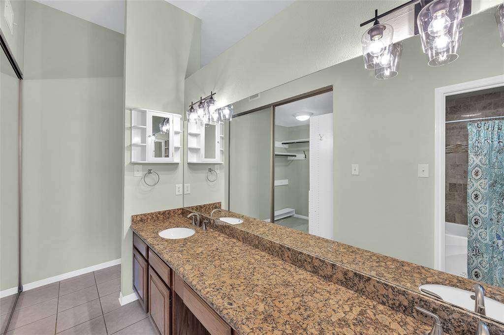 Dual sinks and granite counters in primary bath. Recent light fixtures above the mirrors.