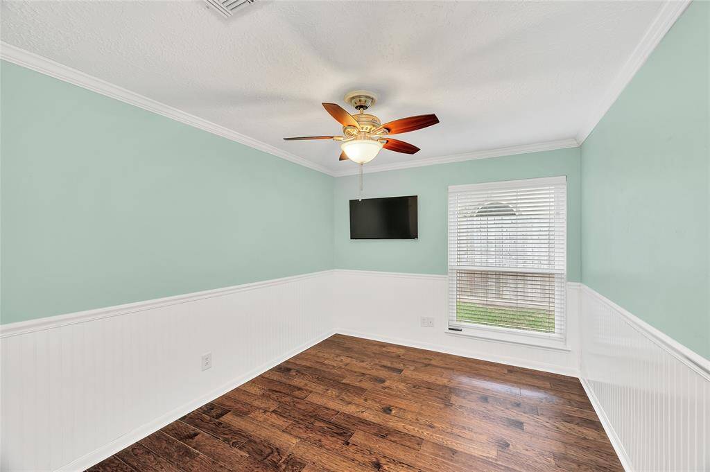 Bedroom #2 with wainscoting and wood floors. TV stays.