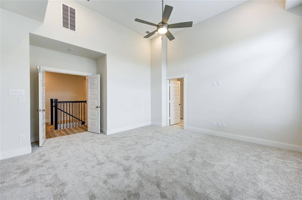 From this angle, the spaciousness of the primary bedroom is accentuated by the soaring high ceilings, which add a sense of grandeur and openness to the room.
