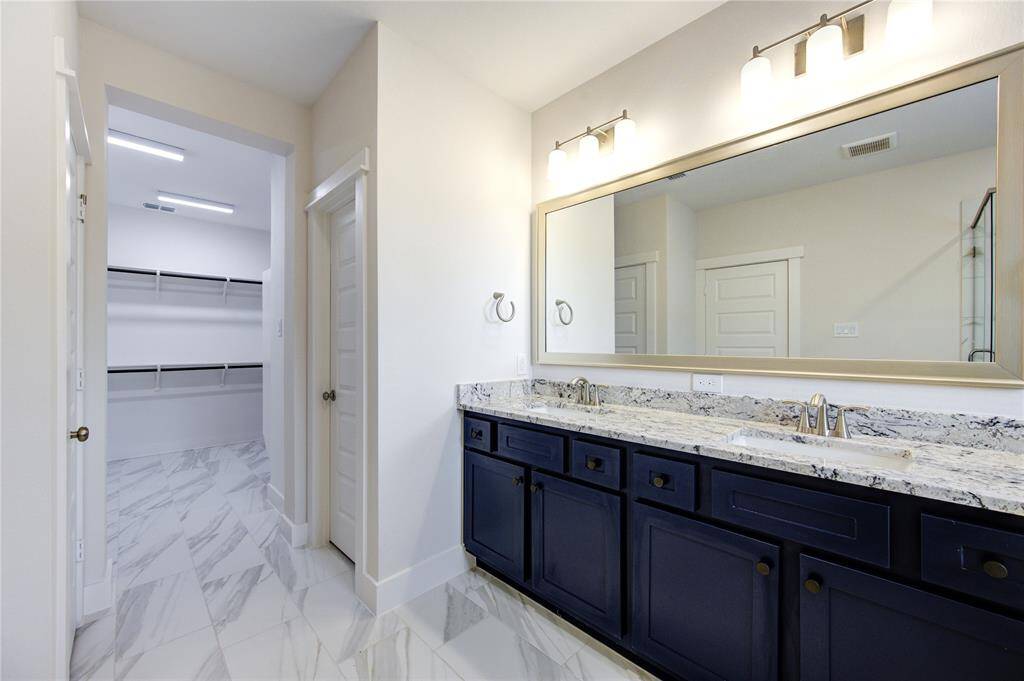 The primary bathroom is a true showstopper, featuring stunning blue cabinets that add a bold pop of color and a touch of sophistication. These modern cabinets are complemented by sleek, contemporary finishes throughout the space.