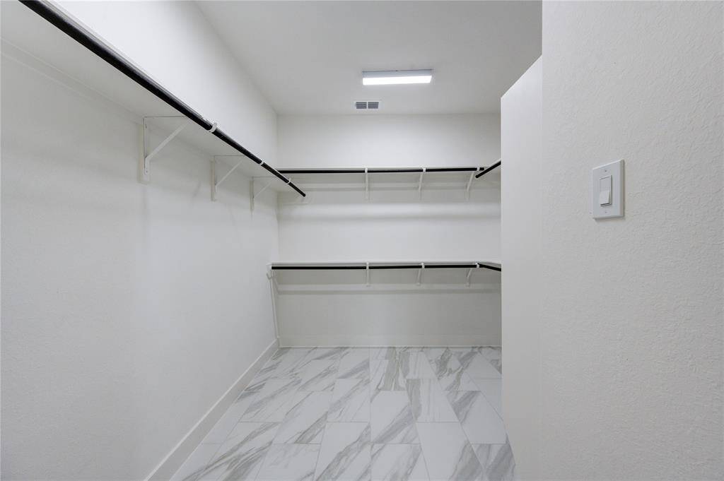 Adjacent to the primary bedroom, the spacious walk-in closet offers plenty of room for storage and organization. Designed with functionality in mind, it features custom shelving and hanging spaces to keep your wardrobe neatly arranged.