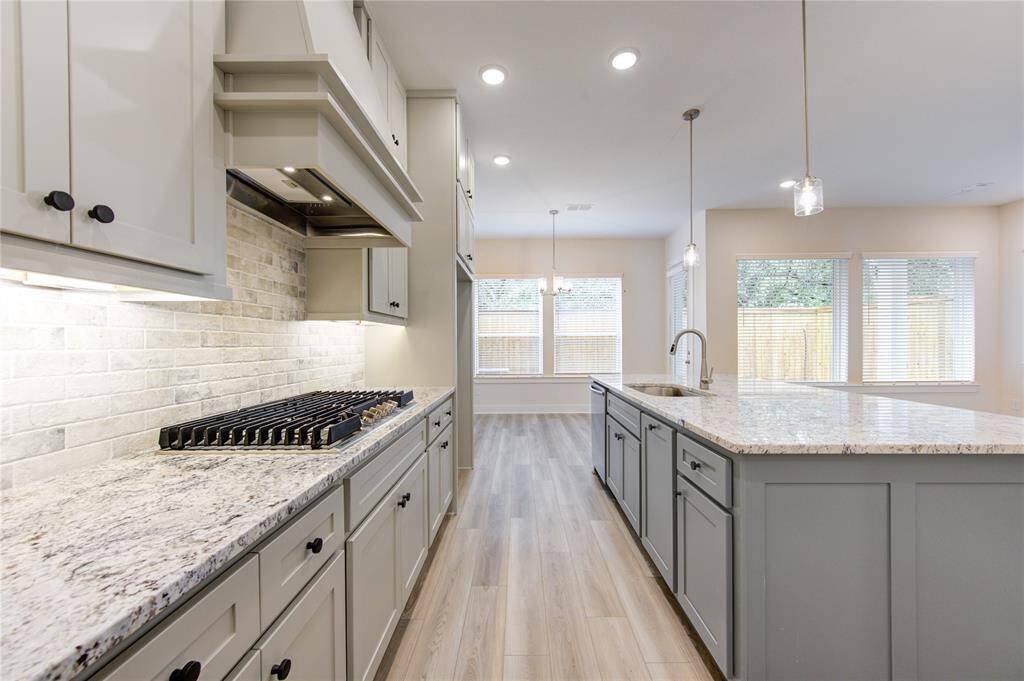 Highlighting a chef's dream setup, the kitchen includes stainless steel appliances, a gas range, soft-close cabinets, a walk-in pantry, and a stylish tile backsplash. The island offers additional prep space and doubles as a breakfast bar for casual dining.
