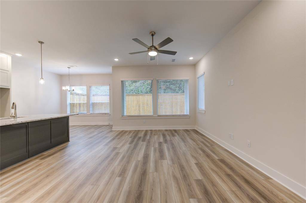 The spacious living room boasts large windows that allow plenty of natural light to fill the space, creating a warm and inviting atmosphere. This area is perfect for both relaxing with family or hosting gatherings, with beautiful flooring and easy flow into the kitchen and dining areas.