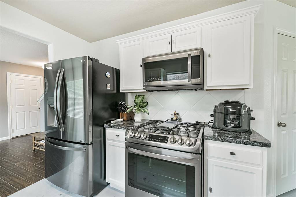 This beautifully updated kitchen features sleek stainless steel appliances—including a gas range and built-in microwave—perfect for home chefs. Crisp white cabinetry and dark countertops create a clean, modern contrast that’s both elegant and efficient.