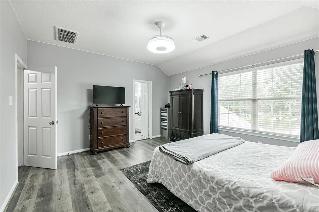 Another view of the primary suite reveals its generous layout and private en-suite bath access. With ample space for furniture and restful views from the large window, this bedroom is both functional and peaceful.