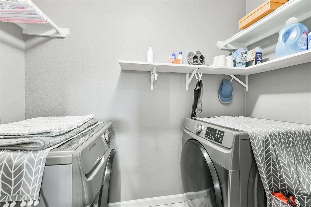 The upstairs laundry room is thoughtfully designed for convenience. It has built-in shelving, and plenty of space to keep things organized and out of sight.