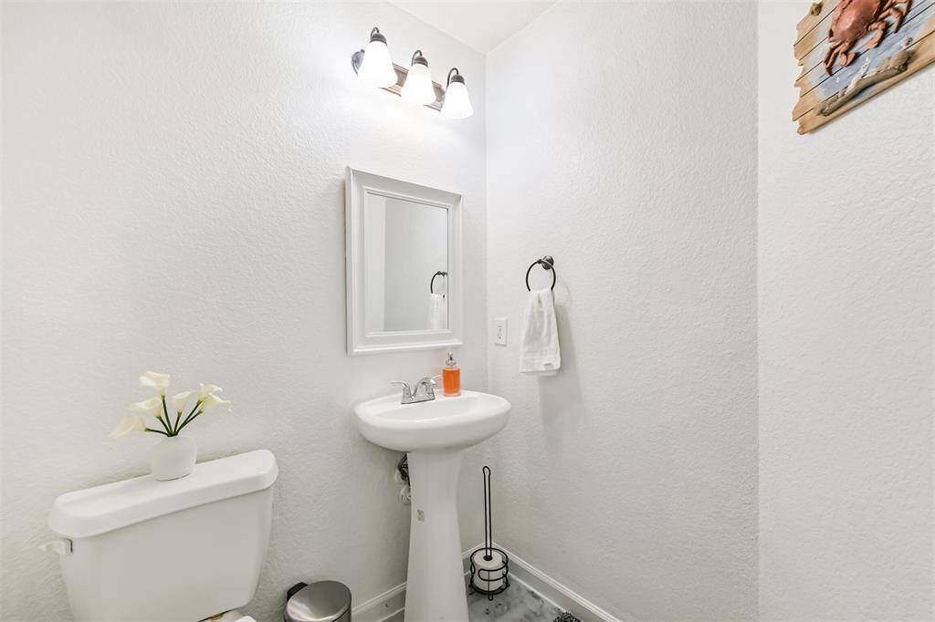 Conveniently located on the main floor, the half bath offers crisp white finishes, a pedestal sink, and stylish lighting—perfect for guests and everyday use.