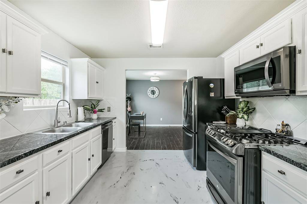 Bright and beautifully updated, this kitchen features sleek black counters, stainless steel appliances—including a gas range—and custom tile flooring, all designed with both style and functionality in mind. A perfect space to cook, gather, and create lasting memories.