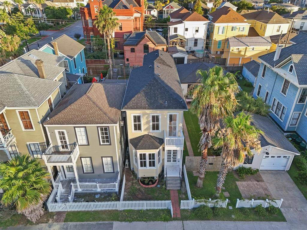 Aerial view showcasing the home's charming facade, palm trees, and ideal location in Galveston’s East End.