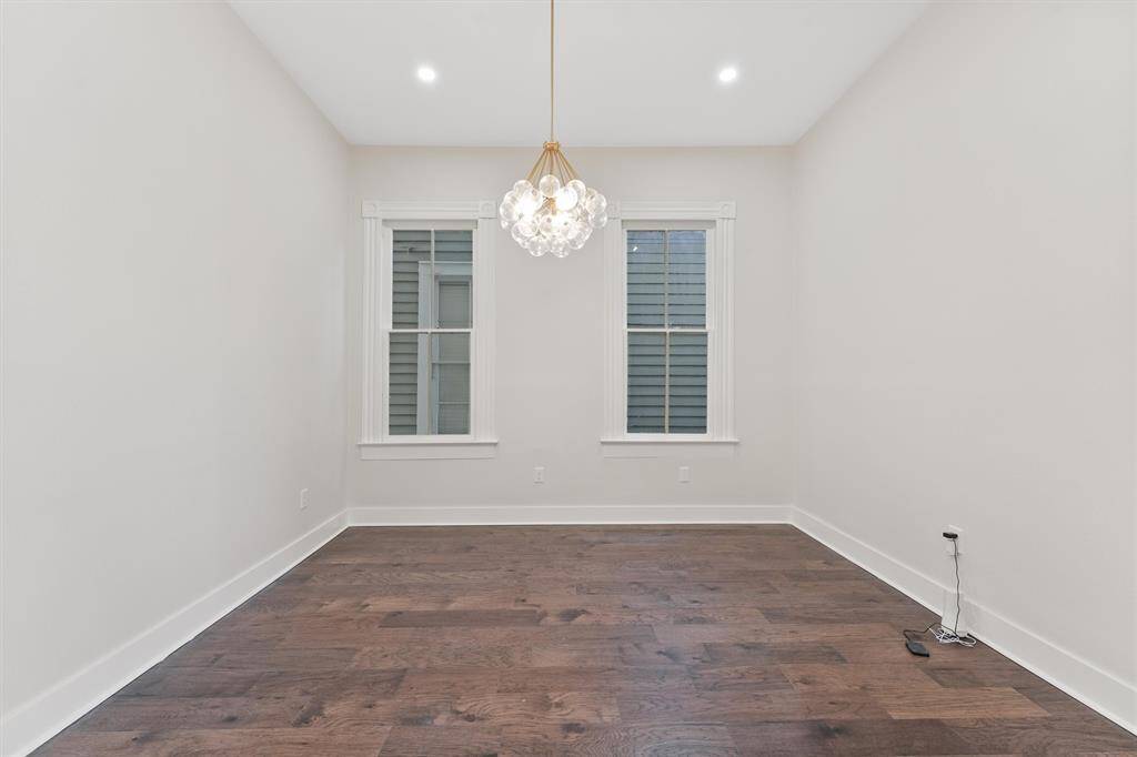 Elegant dining area with designer light fixture and high ceilings, perfect for entertaining or formal meals.