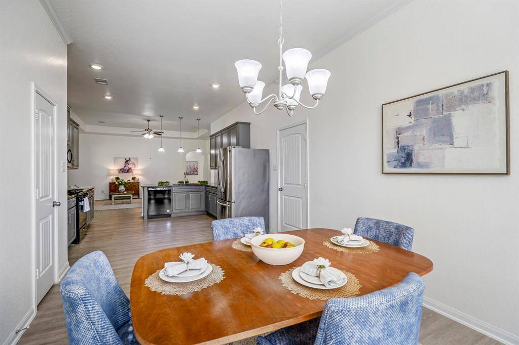 From the opposite corner of the dining room, looking out toward the kitchen, you can spot the garage door conveniently located next to the fridge, offering easy access to the home’s entryway and utility space.