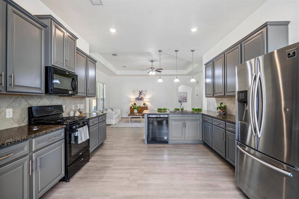 As we move back into the kitchen from the dining area, we see the stove and microwave on the left, surrounded by cabinets offering plenty of storage. To the right, the fridge is nestled next to more cabinets, extending around the corner to the breakfast bar. The sink, positioned across from the breakfast bar, looks out into the living room, with the dishwasher conveniently placed beside it for easy clean-up.