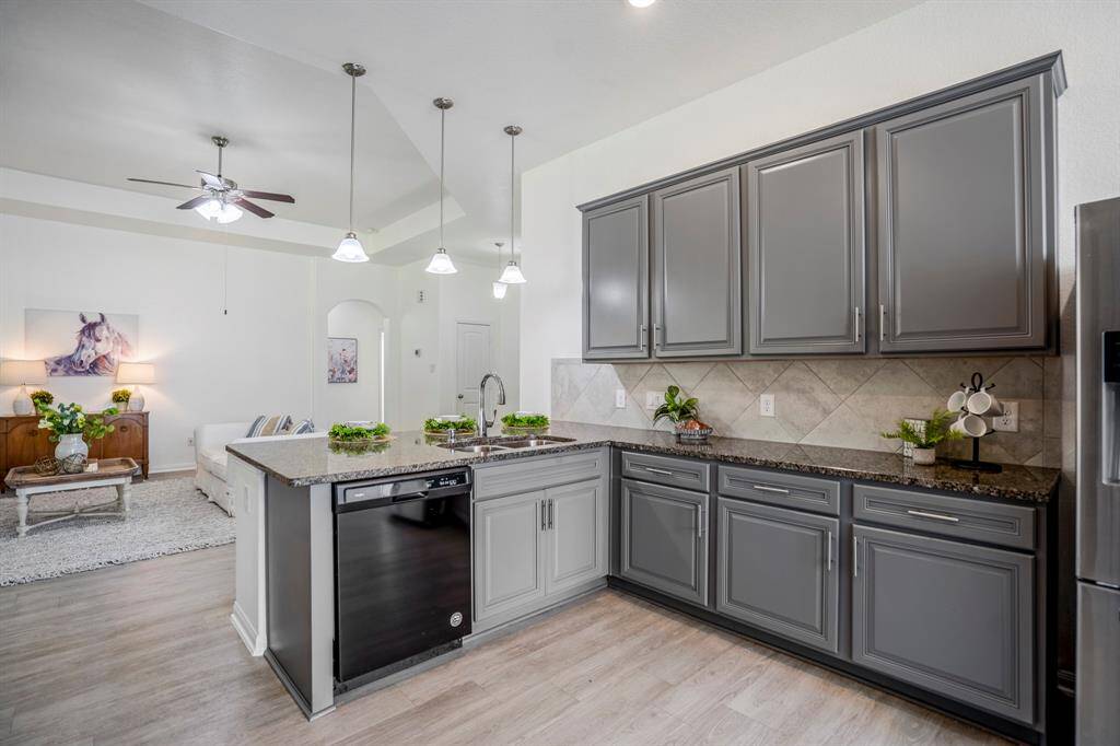 A closer look at the sink area reveals plenty of counter space and cabinets, perfect for meal prep and storage. The open layout offers a seamless flow, with the living room visible just beyond, keeping the space light and connected.