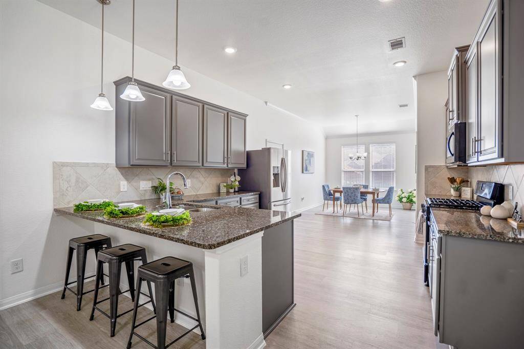 As we move back toward the living room, we get another view of the kitchen, with the breakfast bar creating a clear connection to the dining room just across. The layout keeps the space open and inviting, perfect for easy flow between areas.