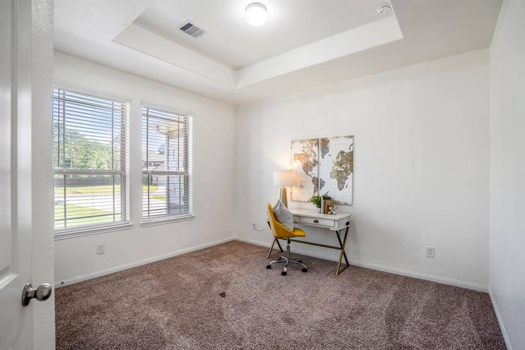 Just off the living room near the kitchen and front door, this bedroom features pop-up tray ceilings and two windows overlooking the front porch, bringing in great natural light.