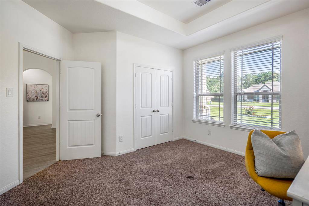 From inside the bedroom, we see the double doors to the closet and, through the doorway, a view across the foyer to the arched entry that leads to the third and fourth bedrooms.
